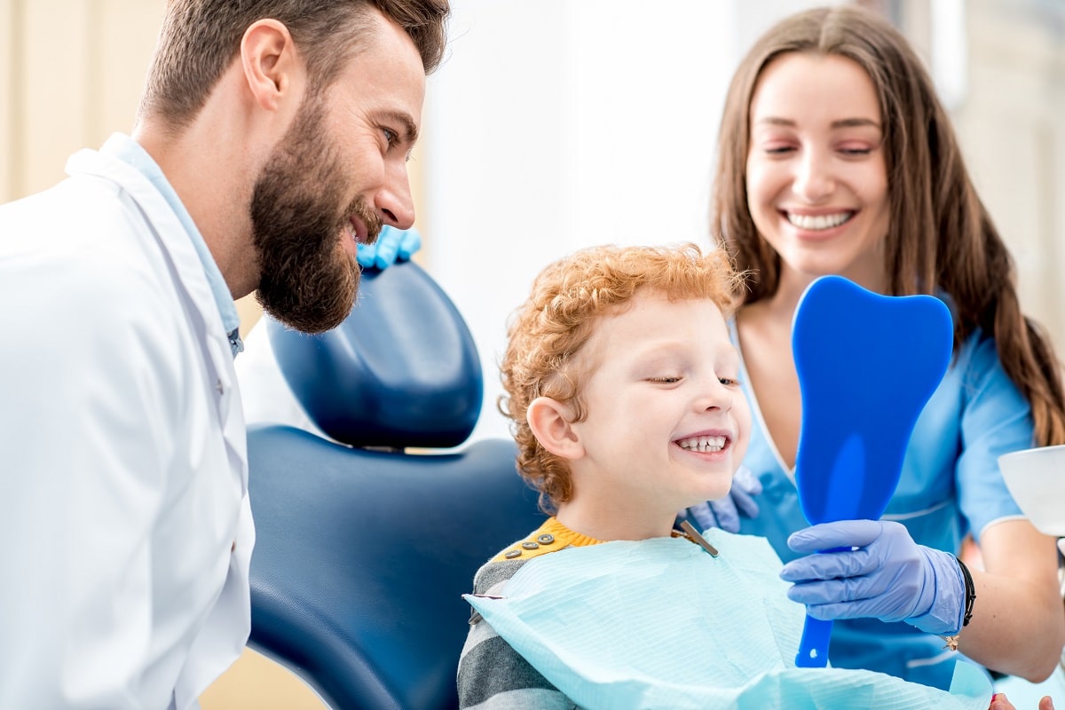 Młody chłopiec patrzący w lustro z uśmiechu na fotelu dentysttycznym